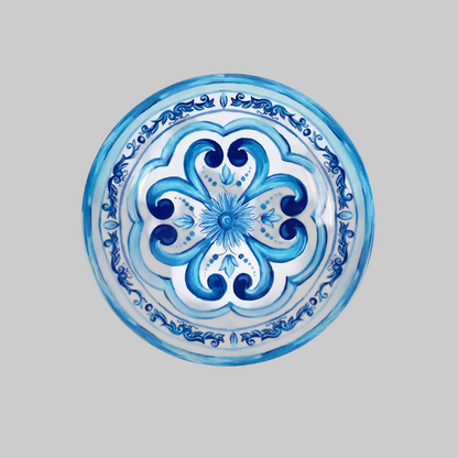 A round decorative plate featuring a hand-painted blue and white floral and scroll pattern, shown against a solid gray background.